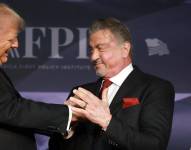 El presidente electo de Estados Unidos, Donald Trump, saluda al actor Sylvester Stallone en el escenario de la Gala del America First Policy Institute celebrada en Mar-a-Lago