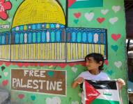 Niño con la bandera junto a pared que dicta Palestina libre.