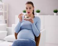 Imagen referencial de mujer embarazada comiendo pastel.