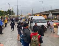 Los guayaquileños esperan una furgoneta, auto o intentan subir en los pocos buses que circulan completamente llenos.