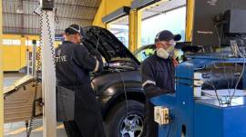 Dos técnicos en uno de los centros de revisión técnica vehicular en Quito.