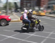 Imagen de dos personas en una moto en una calle de Quito.