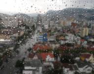 Imagen referencial: Gotas de lluvia en una ventana con el fondo del sur de Quito.