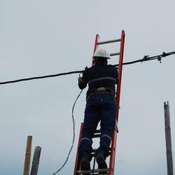 Imagen de un empleado de CNEL durante un trabajo de mantenimiento y cambio de cable.