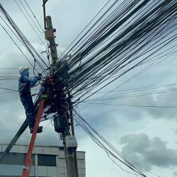 Un obrero acomodando los cables colgados en uno de los postes de la avenida Mariana de Jesús.