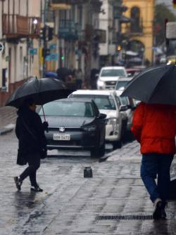 Personas cubriéndose con paraguas en Cuenca.