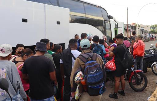 Migrantes hacen fila para abordar uno de los ocho autobuses del 'Corredor emergente de movilidad' en Tapachula (México).