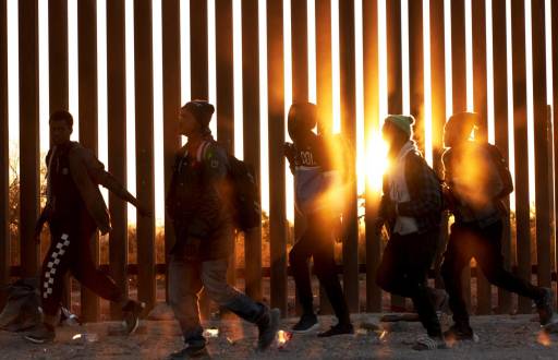 Fotografía de archivo de migrantes que caminan junto al muro en la frontera de EE.UU., y México en Lukeville, Arizona, el 12 de diciembre de 2023.