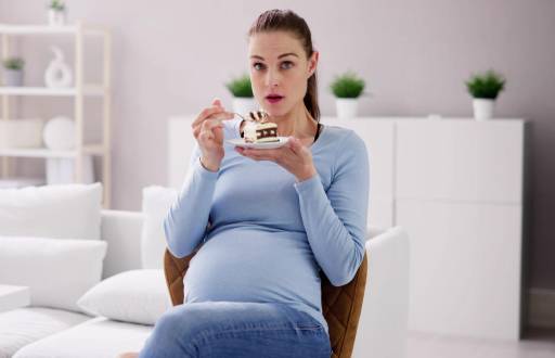 Imagen referencial de mujer embarazada comiendo pastel.