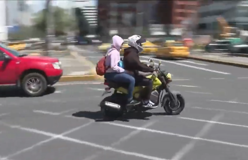 Imagen de dos personas en una moto en una calle de Quito.