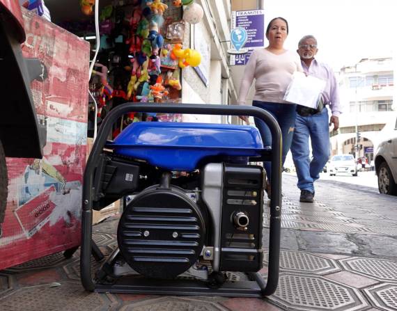 Un generador eléctrico conectado en una vereda, mientras da energía a un negocio.