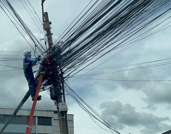 Un obrero acomodando los cables colgados en uno de los postes de la avenida Mariana de Jesús.