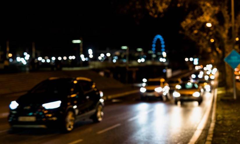 Autos manejando con las luces encendidas para ver en la noche por la carretera.