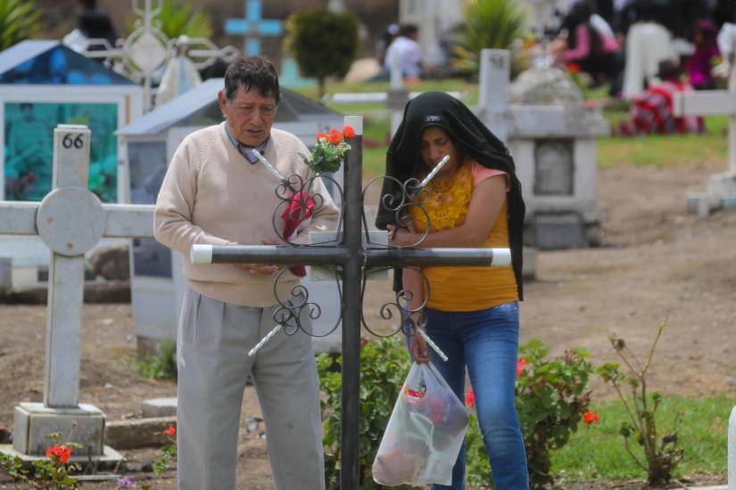 Una pareja reza frente a una tumba durante la conmemoración del Día de Muertos este sábado, en la comunidad de Punin, en Riobamba.