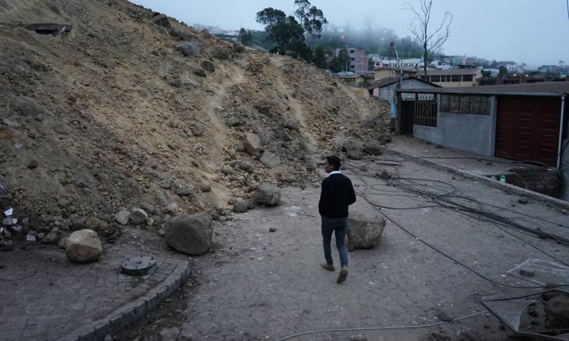 Un hmbre camina ante el cúmula de tierra que se desprendió de una montaña en Alausí y sepultó cinco barrios.