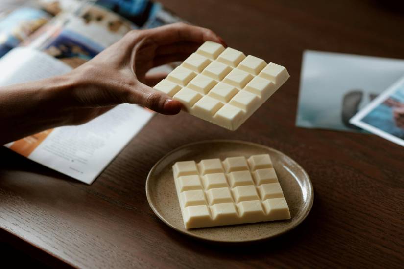 Imagen referencia de mujer sosteniendo una barra de chocolate blanco.