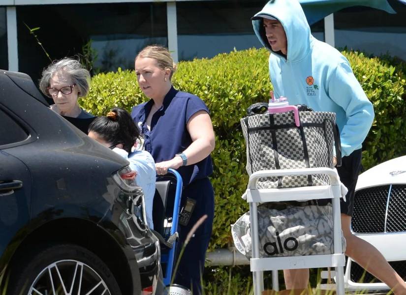 Su esposo, Cole, cargando el equipaje del bebé detrás de ella.