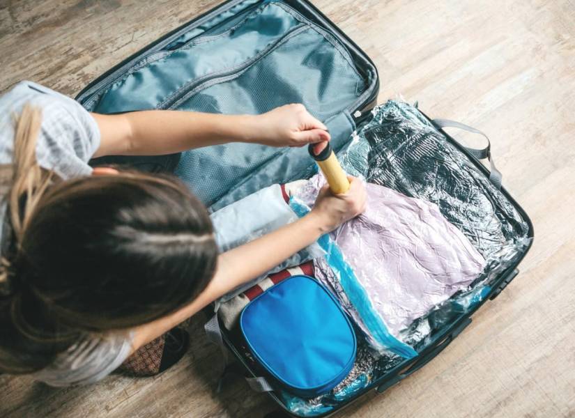 Imagen referencial de mujer empacando su maleta con bolsas al vacío.