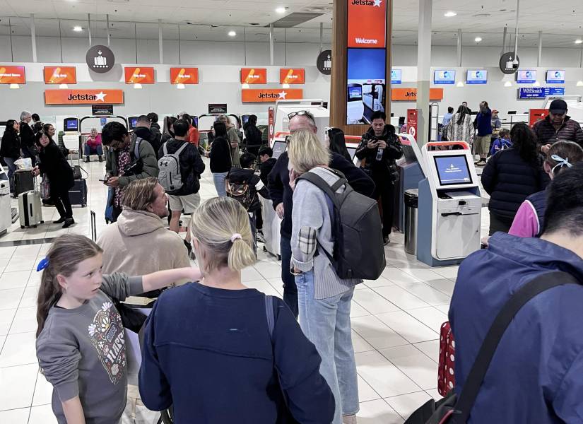 Pasajeros de la aerolínea Jetstar en el aeropuerto de Australia esperan frente a los mostradores cerrados debido al apagón global.