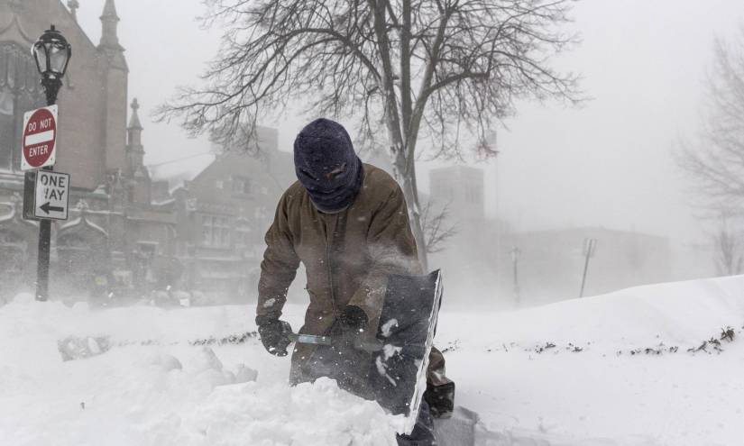 Un hombre retira nieve con una pala durante una tormenta invernal.