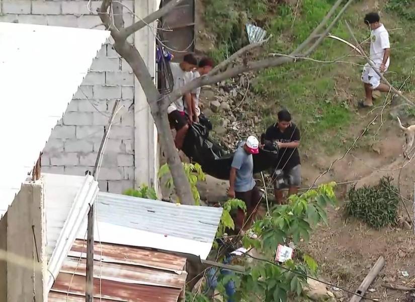 Imagen de personas ayudando a trasladar una víctima de muerte violenta al carro de Medicina Legal de la Policía Nacional, en Balerio Estacio, noroeste de Guayaquil.
