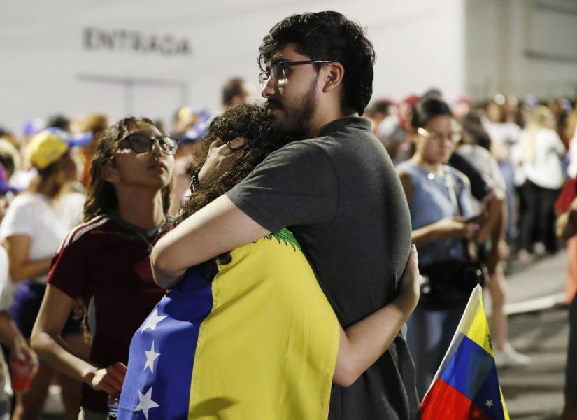 Dos ciudadanos venezolanos se abrazan tras conocer los resultados del primer boletín oficial de las elecciones presidenciales, este domingo a las afueras de la Embajada de Venezuela en Ciudad de Panamá (Panamá).