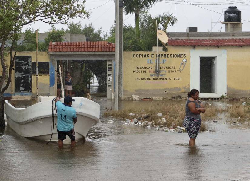 Dos personas caminan por una calle inundada tras el paso del huracán Milton.