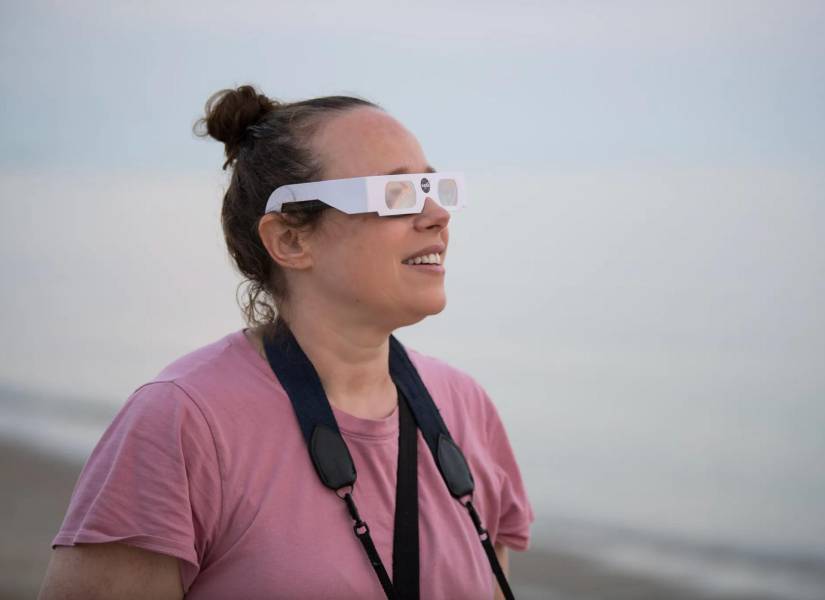 Una mujer usando las gafas especiales diseñadas para ver un eclipse solar.