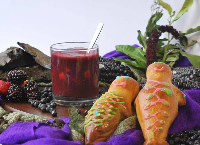 Imagen de archivo de un vaso con colada morada y guaguas de pan.