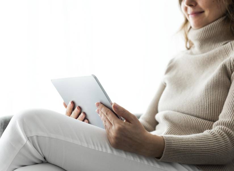 Imagen referencial: Mujer leyendo libros electrónicos en tableta.
