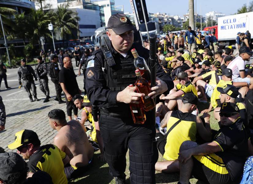 Un integrante de la policía incauta botellas con licor a los fanáticos del Peñarol de Uruguay, luego de ser detenidos en la playa de Pontal en Río de Janeiro.