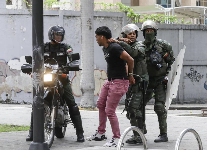 AME6599. CARACAS (VENEZUELA), 30/07/2024.- Integrantes de la Guardia Nacional Bolivariana detienen a un manifestante opositor, este martes, en Caracas (Venezuela). Miles de venezolanos se han concentrado este martes en Caracas, en un acto convocado por la oposición mayoritaria, para rechazar por segundo día consecutivo lo que consideran es un fraude en los resultados oficiales del Consejo Nacional Electoral (CNE), que en la víspera proclamó a Nicolás Maduro como presidente reelecto con el 51,2 % de los votos. EFE/ Ronald Peña