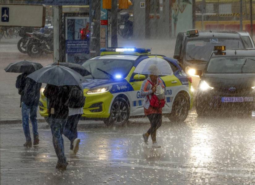 Varias personas se protegen de la lluvia en la Plaza de España de Barcelona este lunes cuando las comarcas de del Garraf y del Barcelonès, en Barcelona, están en aviso rojo de la Agencia Estatal de Meteorología.