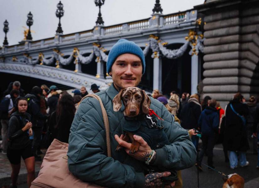 Un hombre lleva un perro salchicha mientras participa en la quinta edición del 'Paris Sausage Walk'