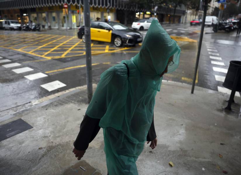 Un hombre camina bajo la lluvia por el centro de Barcelona este lunes cuando las comarcas de del Garraf y del Barcelonès, en Barcelona, están en aviso rojo de la Agencia Estatal de Meteorología.