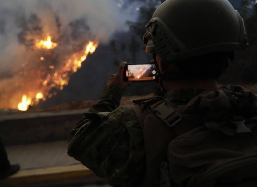 Un integrante del Ejército de Ecuador toma imágenes con su teléfono de un incendio forestal este martes, en el sector de Guápulo en Quito (Ecuador).