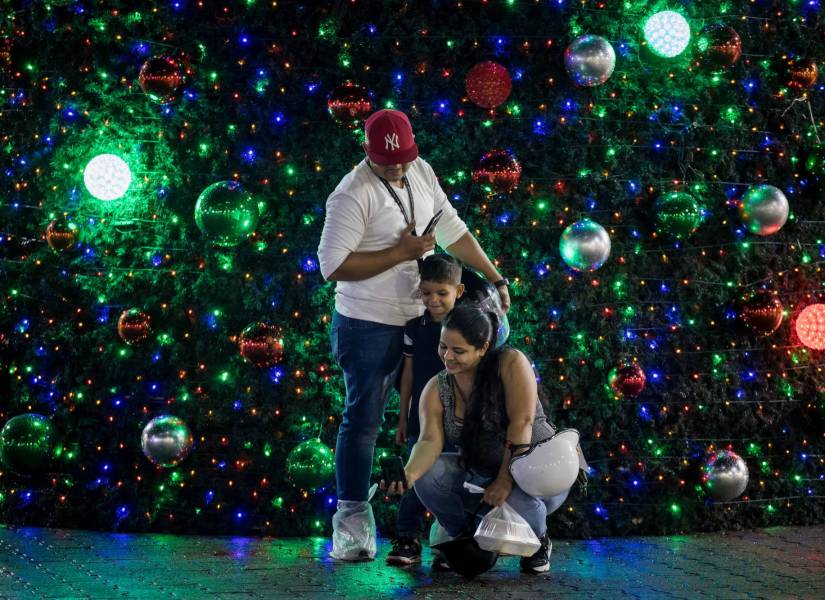 Personas se toman una fotografía junto a un árbol navideño este lunes, en Caracas (Venezuela).