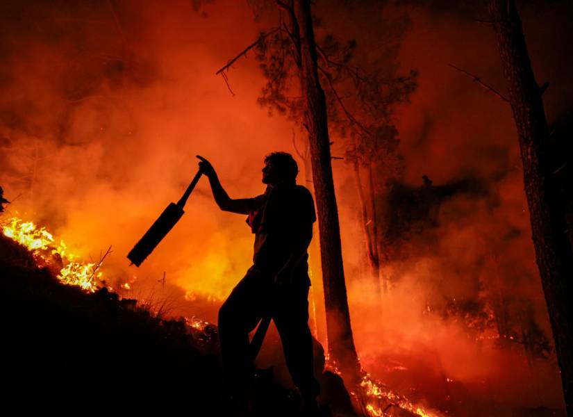 Un hombre parte de un grupo de bomberos combate un incendio forestal