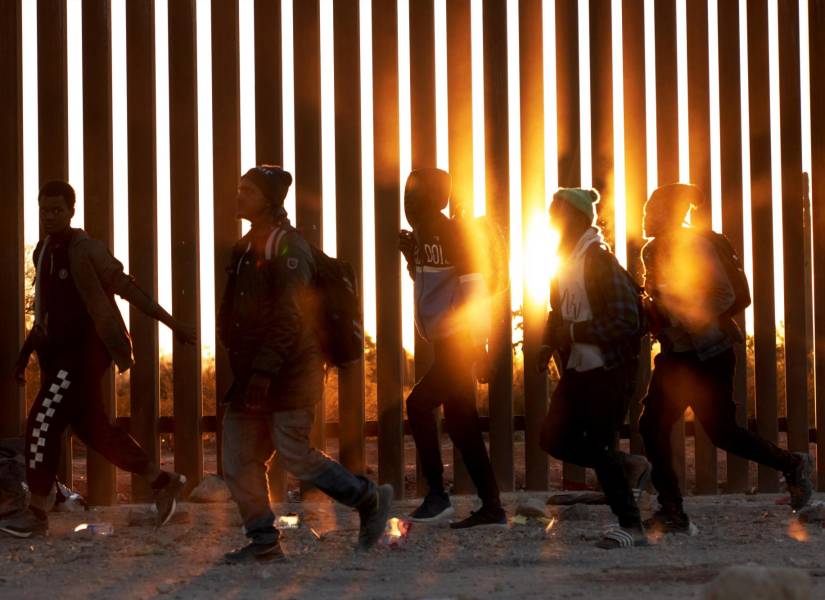 Grupo de migrantes caminando en el borde entre México y Estados Unidos