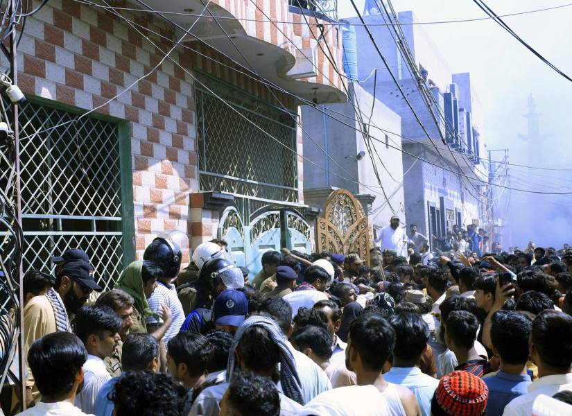 La gente se reúne en el lugar después de que una turba violenta atacara a una comunidad cristiana