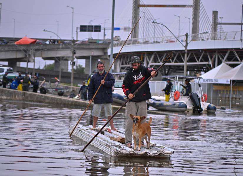 Dos hombres utilizan unas tejas para navegar en una zona inundada