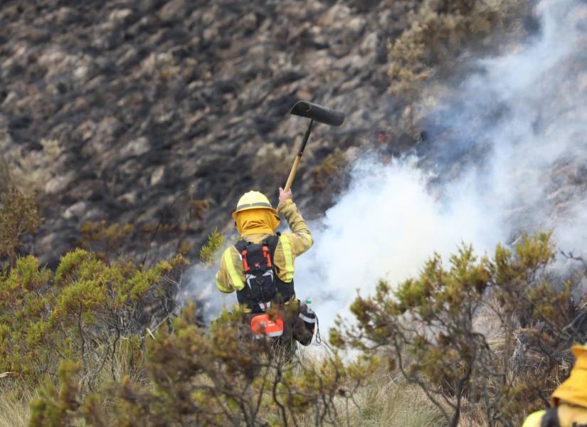 Imagen de un bombero apagando una zona del incendio en Quito.