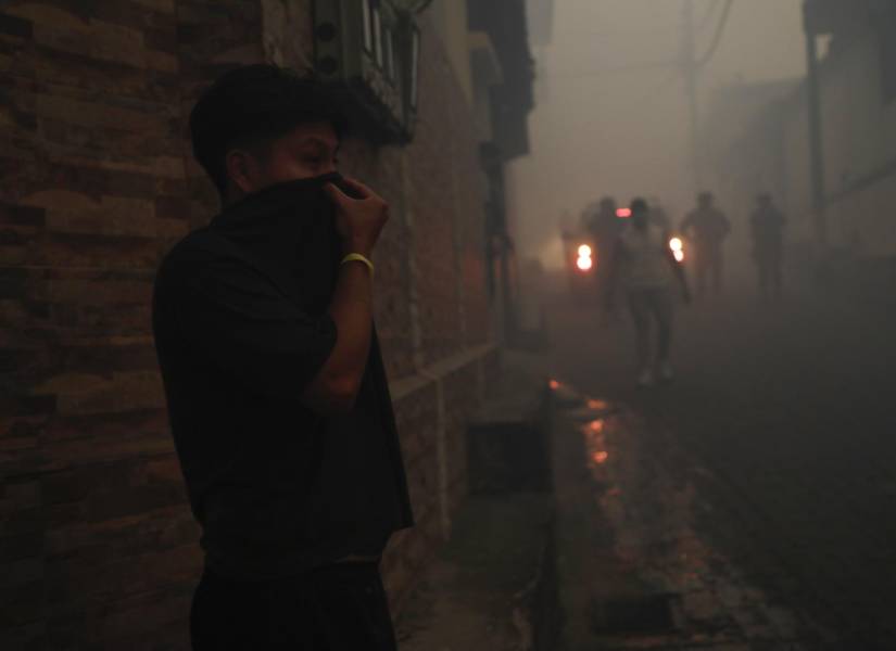 Una persona se protege del humo producido por un incendio forestal este martes, en el sector de Guápulo en Quito.