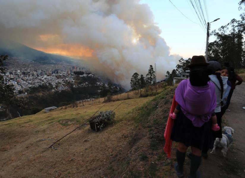 Personas observan un incendio forestal este martes, en el sector de Guápulo.