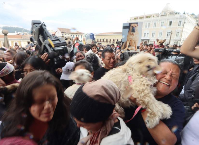 Momento en que el padre lanza el agua bendita para las mascotas.