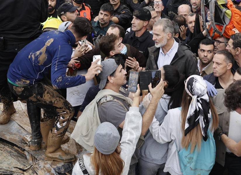 El rey Felipe habla con vecinos afectados por la riada, durante su visita a Paiporta este domingo.