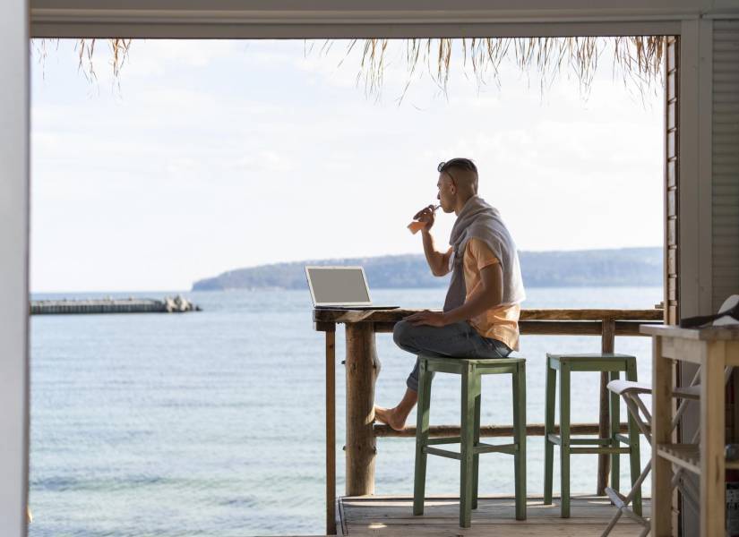 Imagen referencial de hombre trabajando remotamente desde la playa.