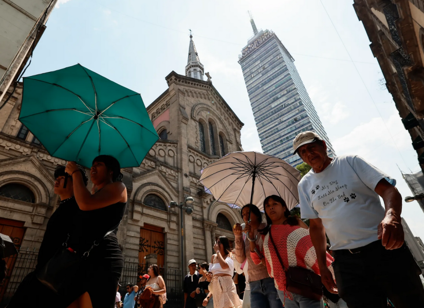 Fotografía de archivo donde se observan varias personas caminar con sombrilla para protegerse del sol, en Ciudad de México.