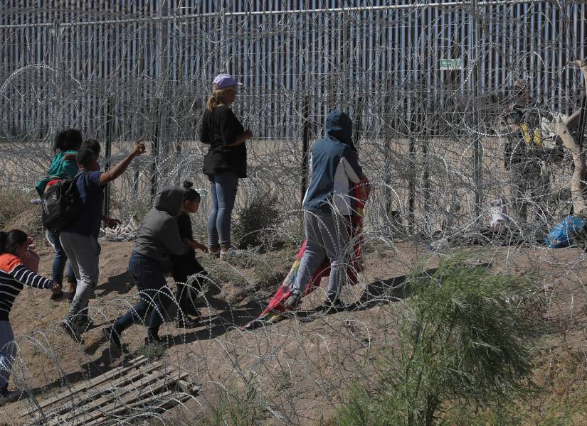 Migrantes que esperan entre los alambres de púas mientras un agente estadounidense vigila en Ciudad Juárez, Chihuahua (México).