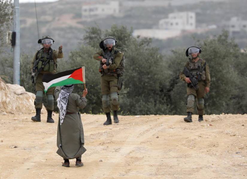 Soldados y un niño con una bandera de Palestina